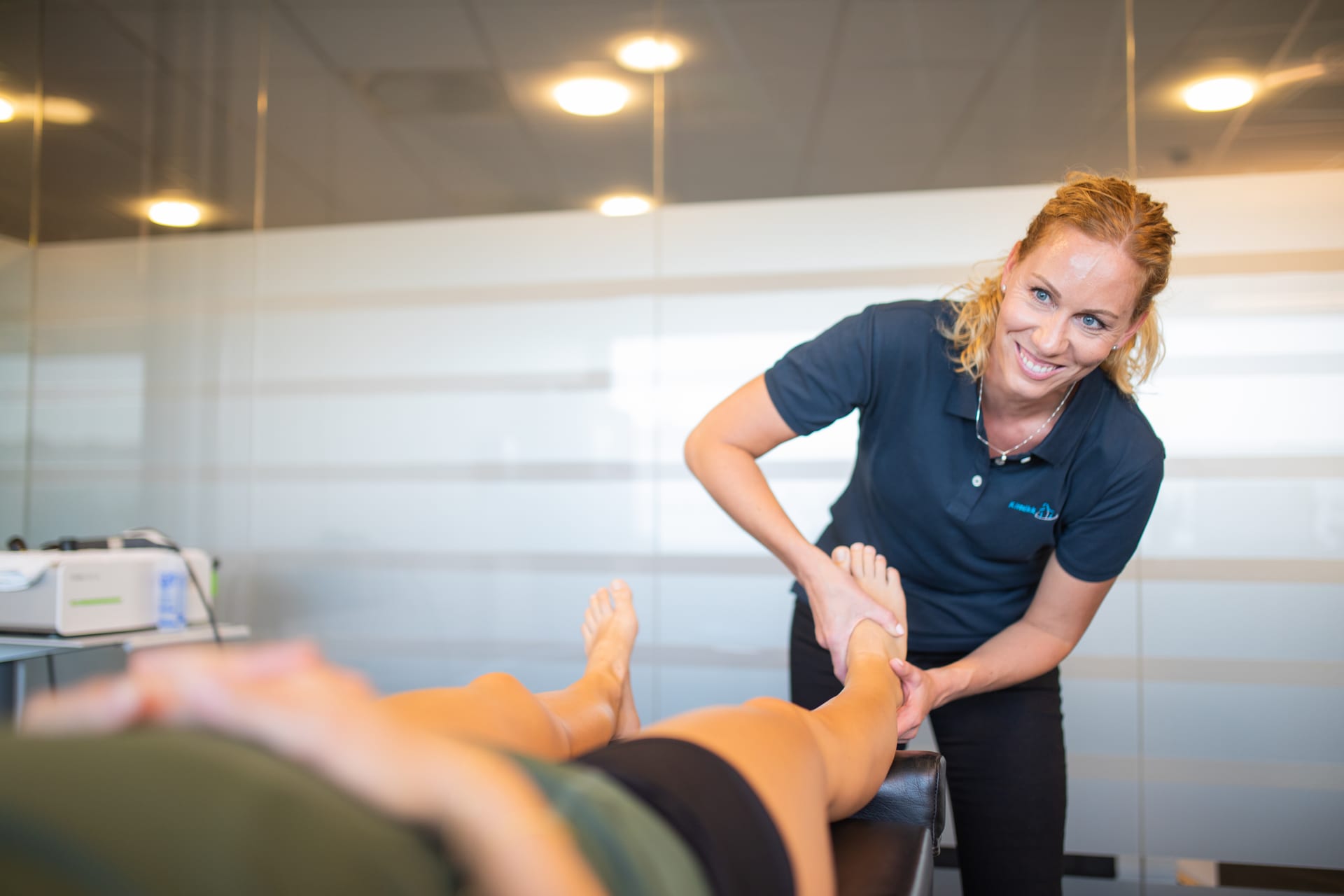 Kiropraktor Camilla Bjørnsen Tjensvoll smiler mens hun behandler foten til en pasient ved Klinikk Libra